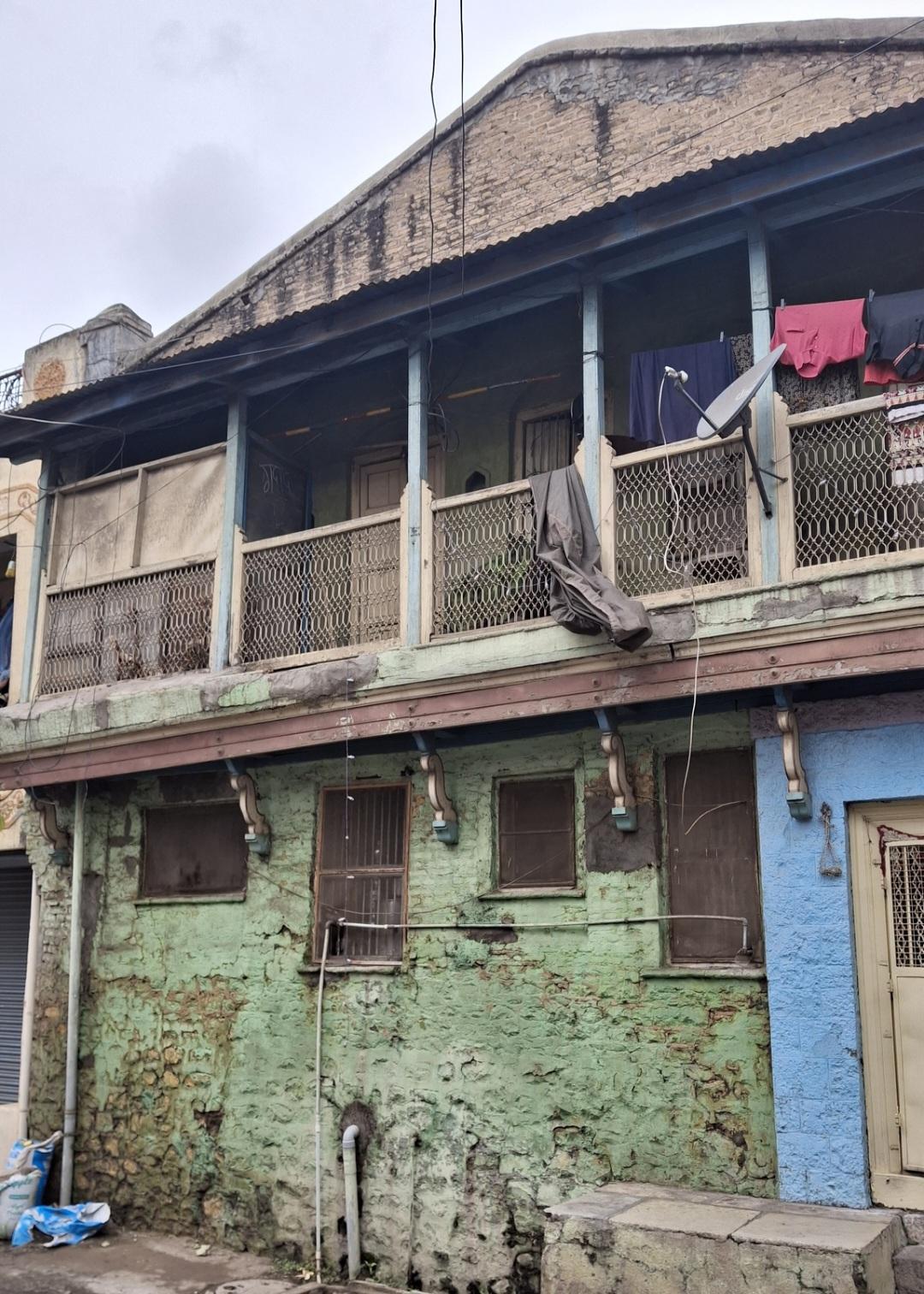 The balcony projection features a wooden cantilever structure, visible beneath the unplastered, triangular parapet. (Source: CKA Archives)