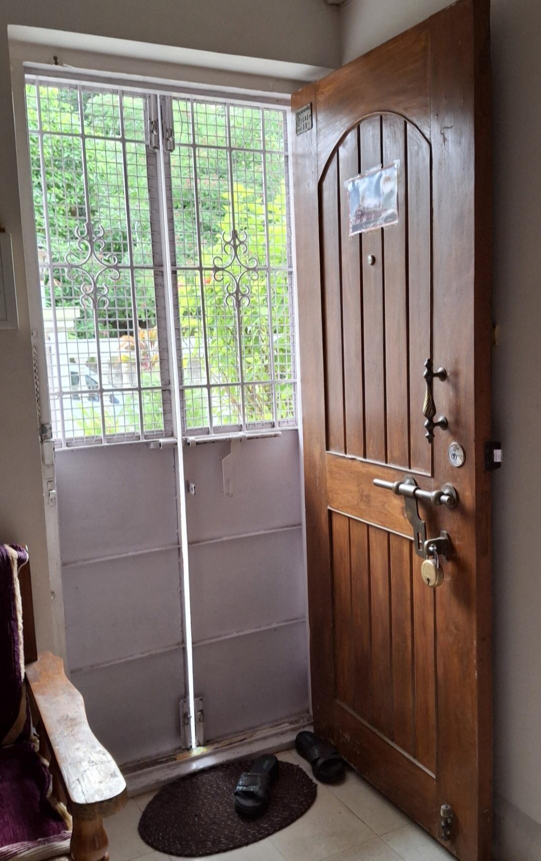 The teak wood main door with brass handles and an external mild steel grill door for security. (Source: CKA Archives)