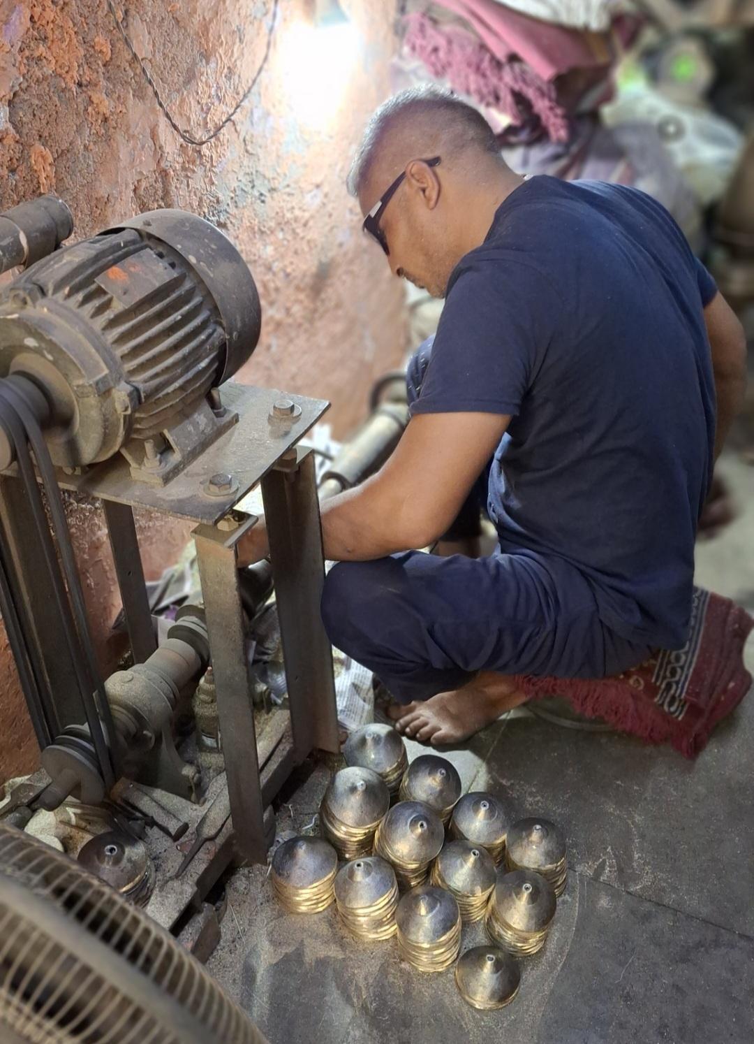 A blacksmith operating a machine which carves circular shapes on the Taal and gives it a polished, finishing look. (Source: CKA Archives)