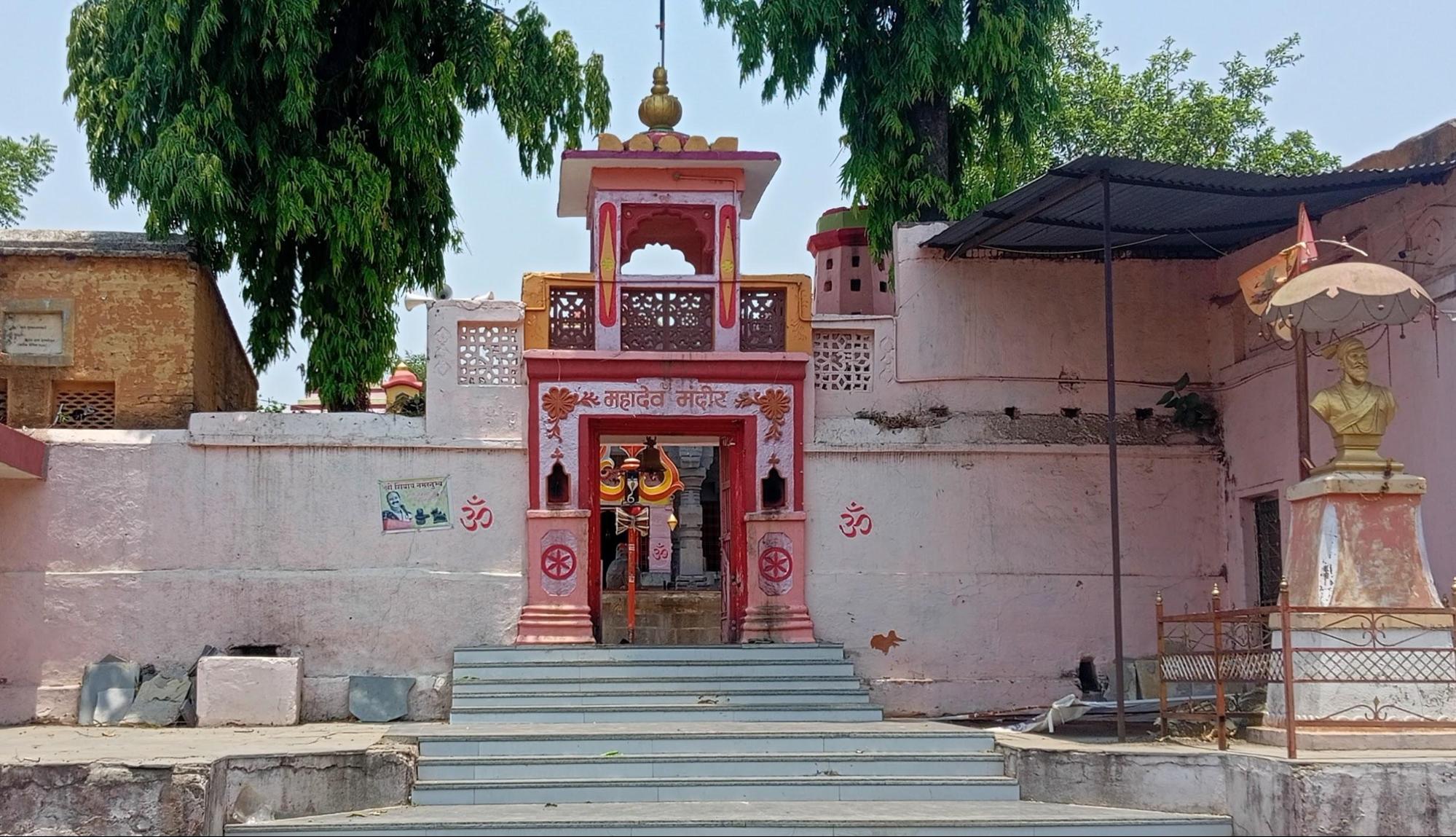 The entrance of the Mahadev Mandir, featuring a brick and mortar wall (a later addition) painted in a faded pink color. (Source: YouTube @/RJ Dipak Wankhade)