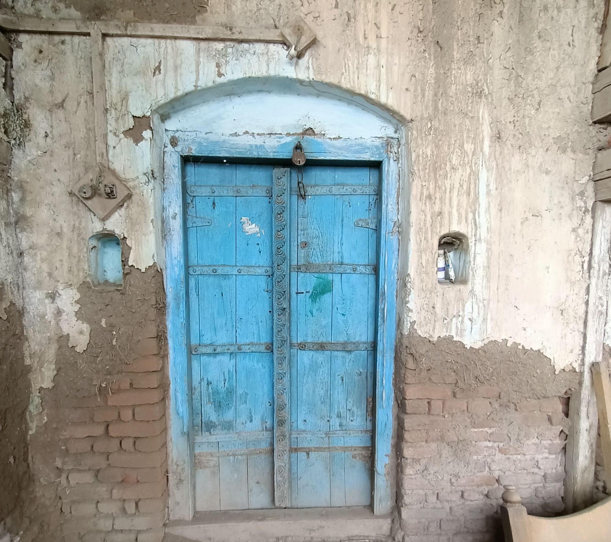 Blue-painted double door with central divider, set within a curved frame against exposed brickwork. (Source: CKA Archives)