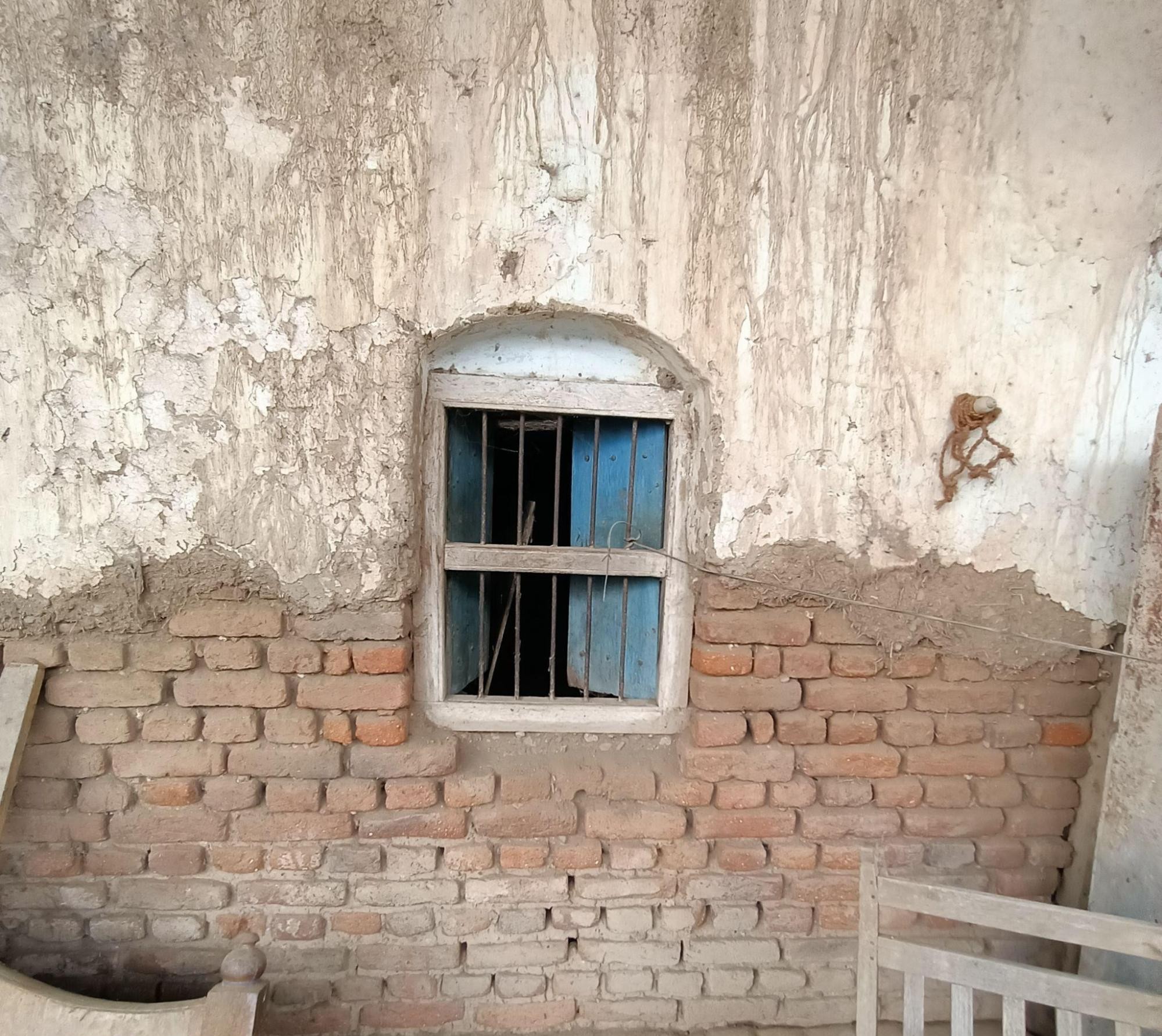 Small arched window with blue wooden frame set above exposed brickwork. (Source: CKA Archives)
