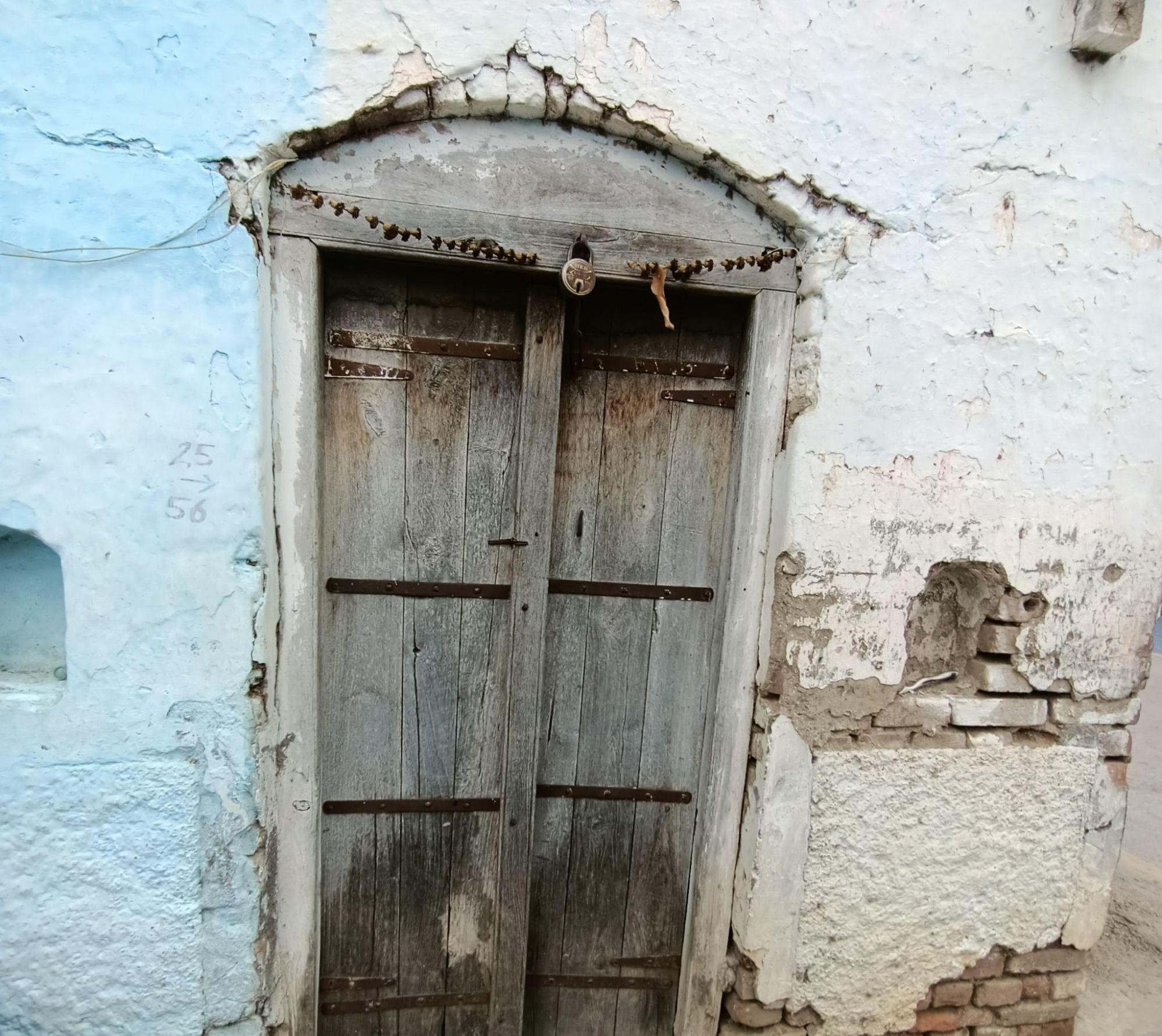 Traditional double-doored wooden entrance showing natural aging, with central divider and horizontal planks. (Source: CKA Archives)