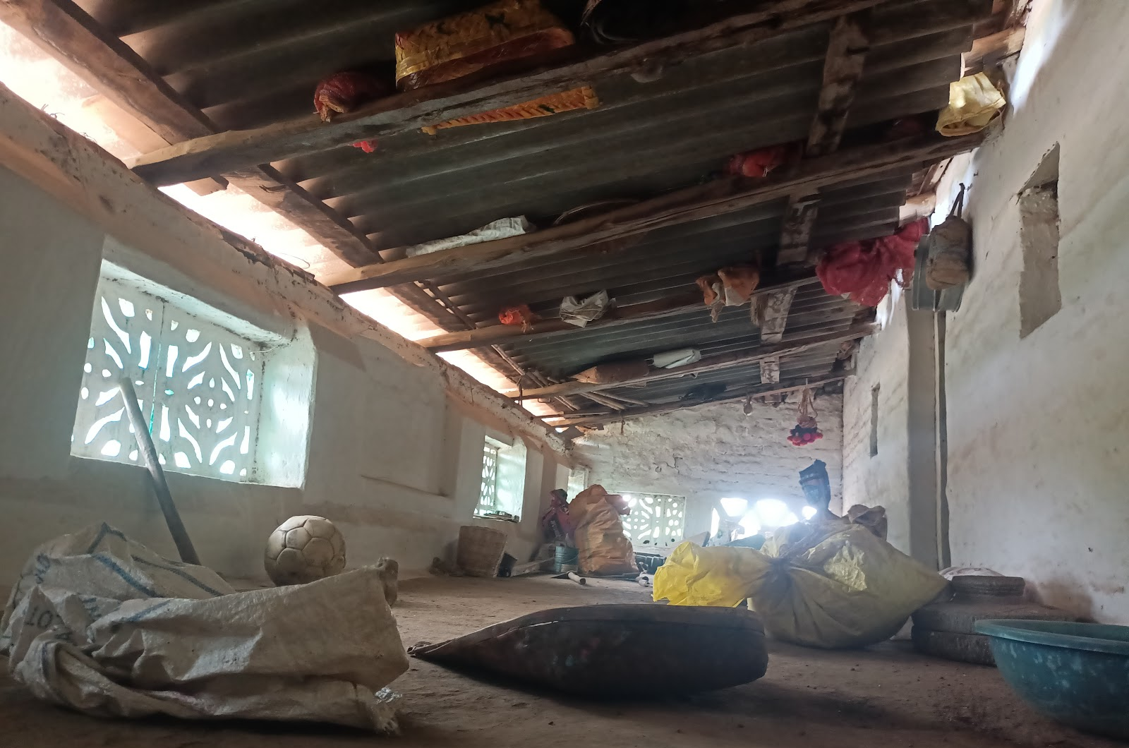 Wider view of the same roofing structure with visible framework, featuring a decorative jali ventilation window and household items hung from the beams. (Source: CKA Archives)