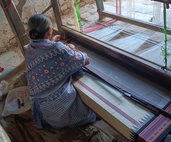 A weaver at work on a traditional pit loom with a Nagpuri wooden dobby, used in the making of Karvati Kinar sarees at a Vemshala artisan collective.[2]