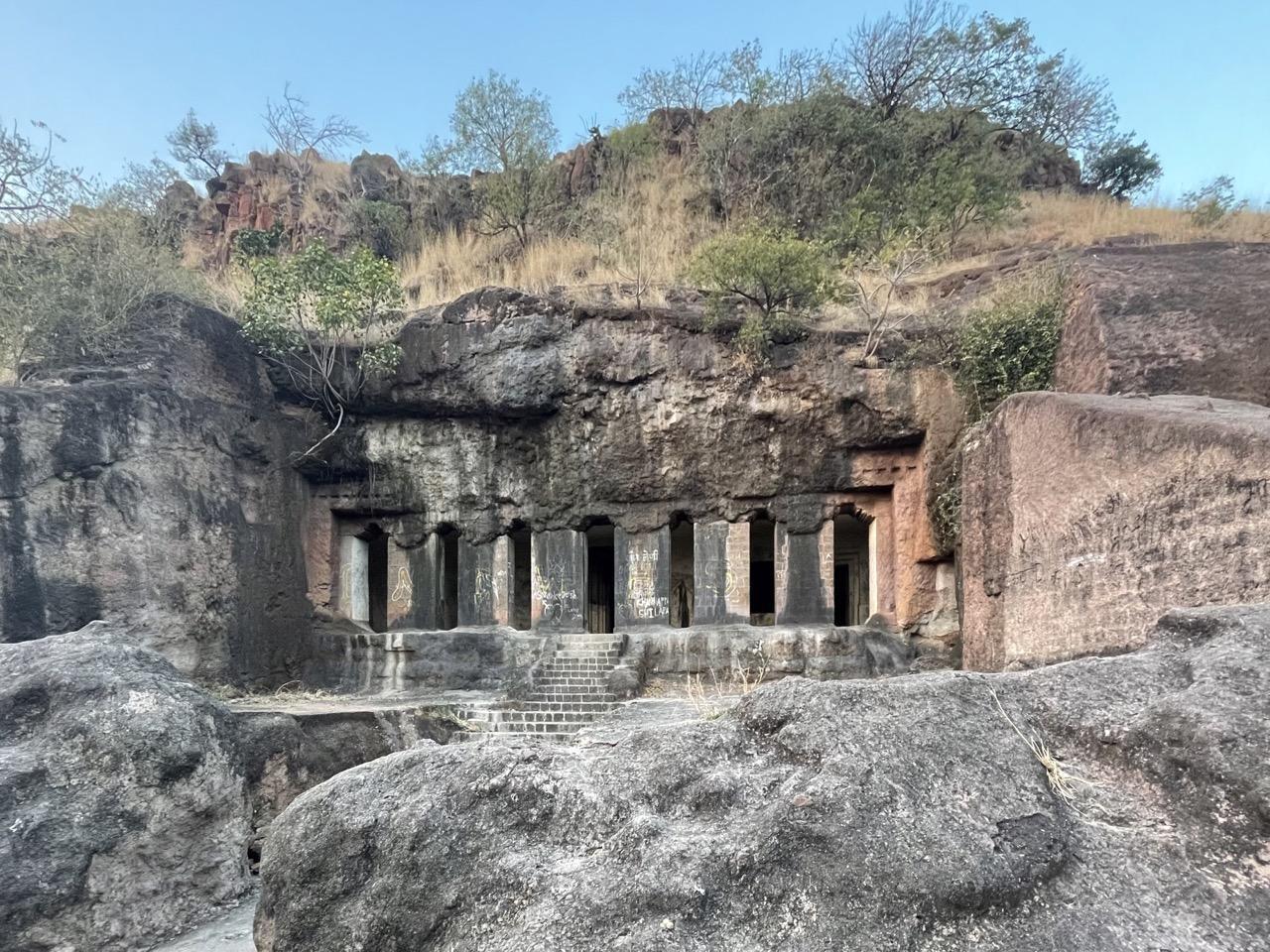 Entrance steps leading to the Dharashiv Caves, carved into the hillside and surrounded by seasonal vegetation. (Source: CKA Archives)