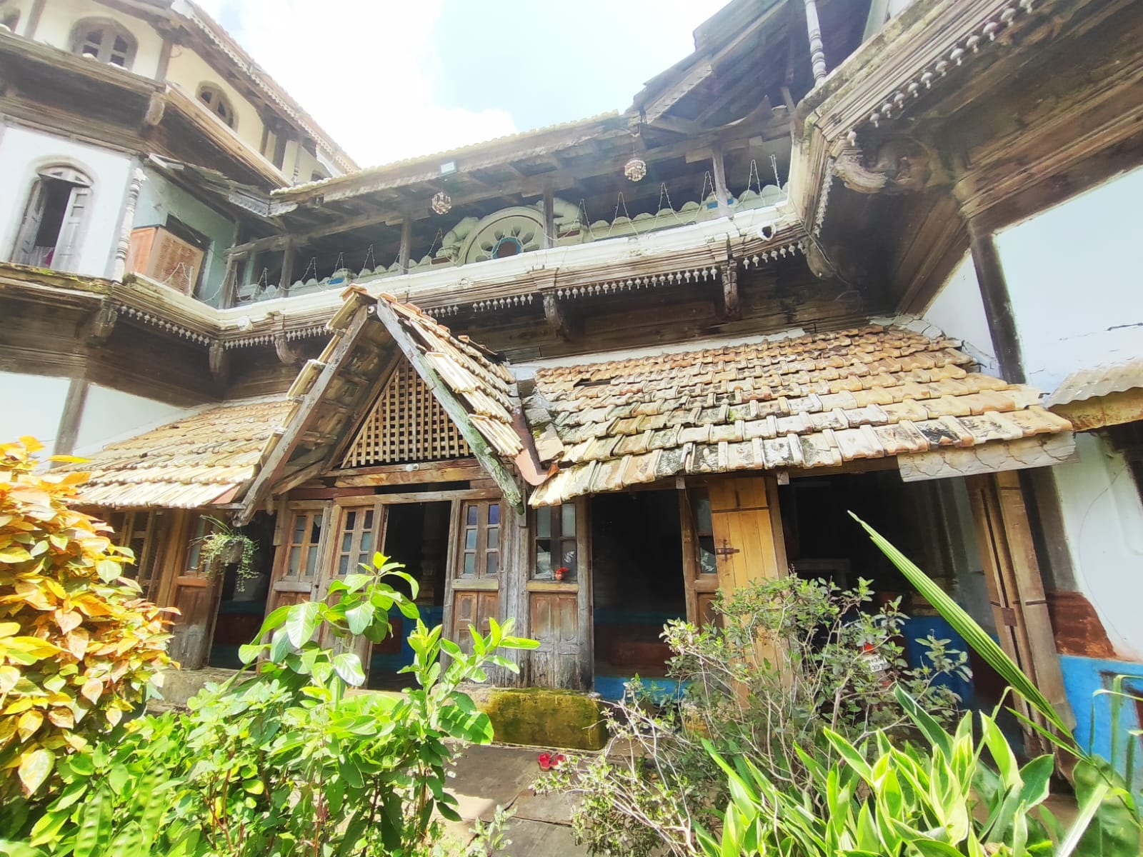 Traditional wooden entryway of Doye Wada featuring a triangular gabled roof with latticed woodwork (jali) beneath the eaves. The entrance consists of wooden double doors and symmetrical windows on either side. (Source: CKA Archives)