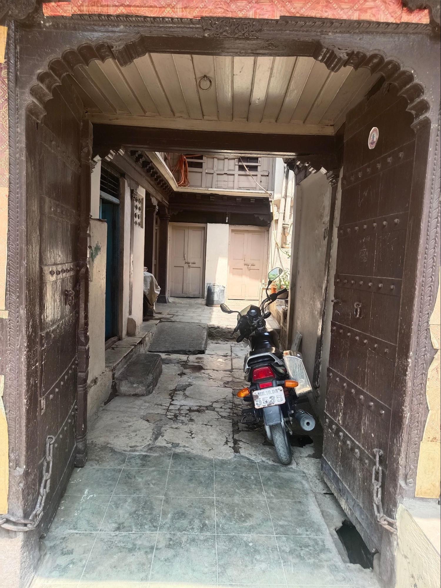 A view of one of the entrances to the Wada, featuring an intricately carved wooden arch framing a solid wooden door. The entrance is characteristic of traditional Wada architecture, with its emphasis on craftsmanship and its large scale. (Source: CKA Archives)