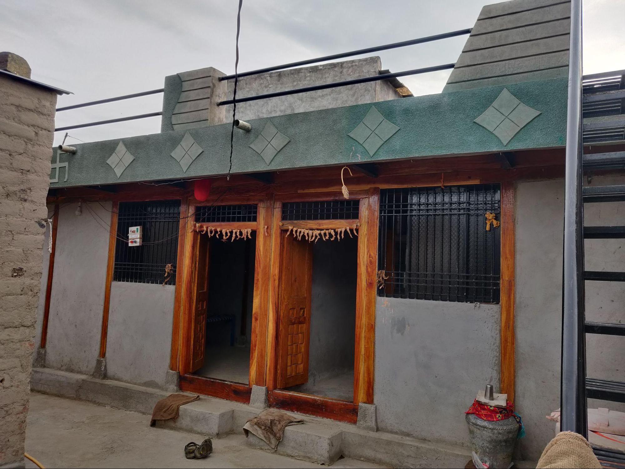 Double-shuttered doors made of polished neem wood, featuring simple carvings and clerestory windows above for ventilation. (Source: CKA Archives)