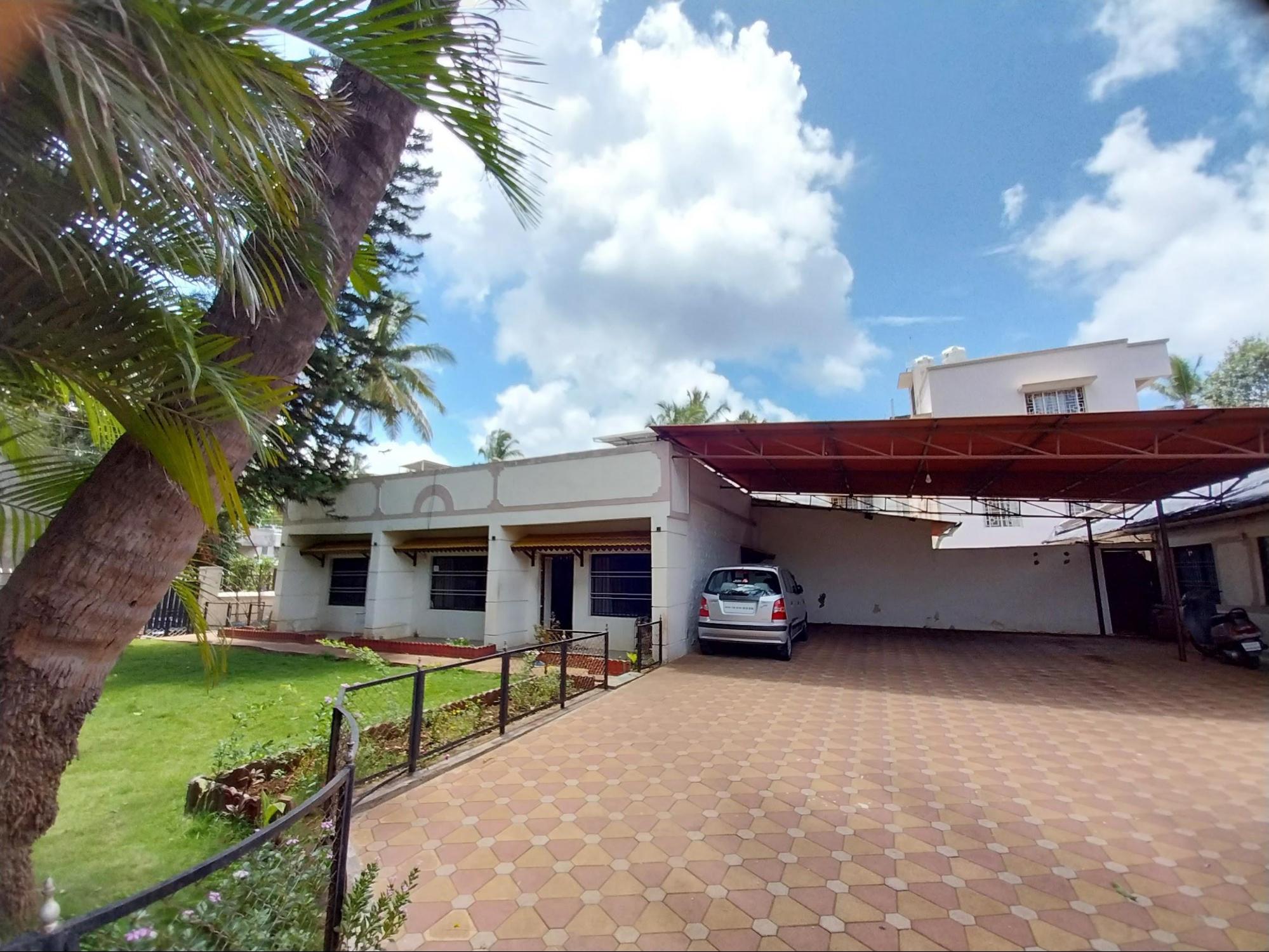 The home’s layout features a centrally positioned main building, complemented by a front lawn, a garage or parking area, and utility spaces arranged along the sides. (Source: CKA Archives)