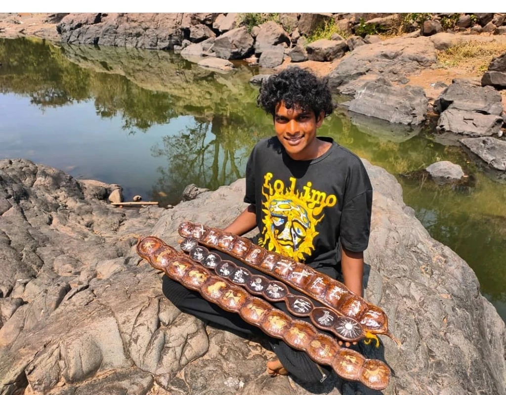 Dinesh Barap holding hand-painted royal poinciana seed pods featuring Warli art, created using natural pigments sourced from local plants.[11]