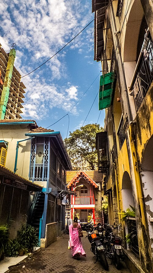 A narrow lane in Khotachiwadi with houses painted in vibrant colors, set amidst greenery.[19]