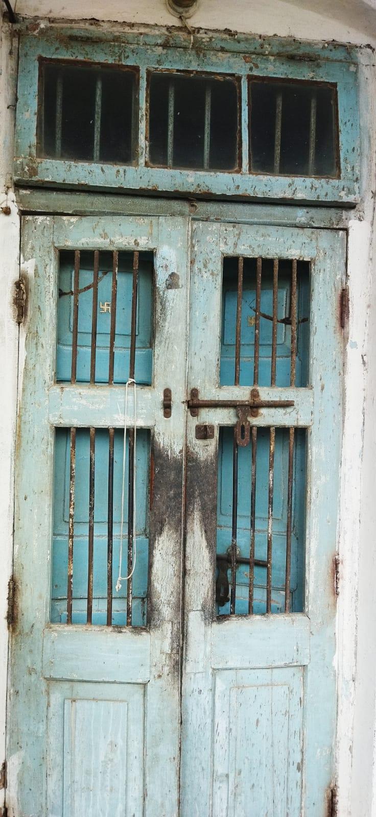 Double-shuttered blue entrance with an outer safety door featuring iron grills, an inner wooden door and a clerestory window above for ventilation. Source: CKA Archives