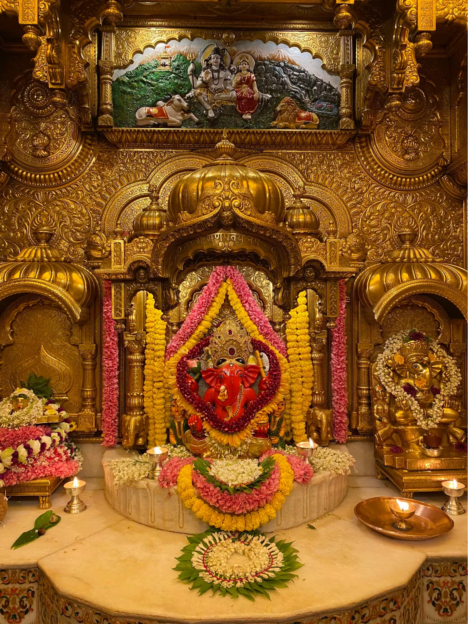 The gold-plated garbha at the Siddhivinayak Mandir, with the murti of Shri Ganesh (centre) and an engraving sculpture of Shiv and Parvati above[28]