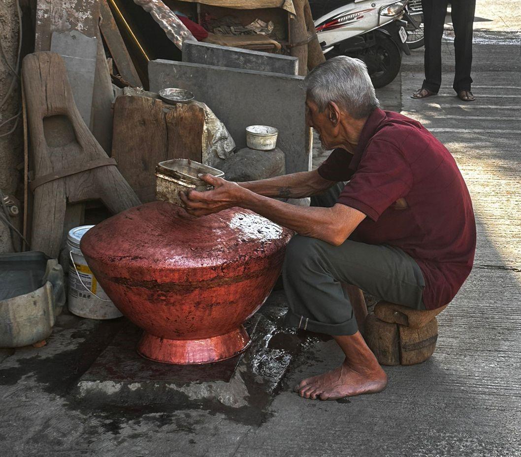 An artisan performing kalai and malam, a traditional tin-coating process used to extend the life of brass and copper vessels. This practice remains one of the few surviving repair techniques in Tambat Ali. (Source: CKA Archives)