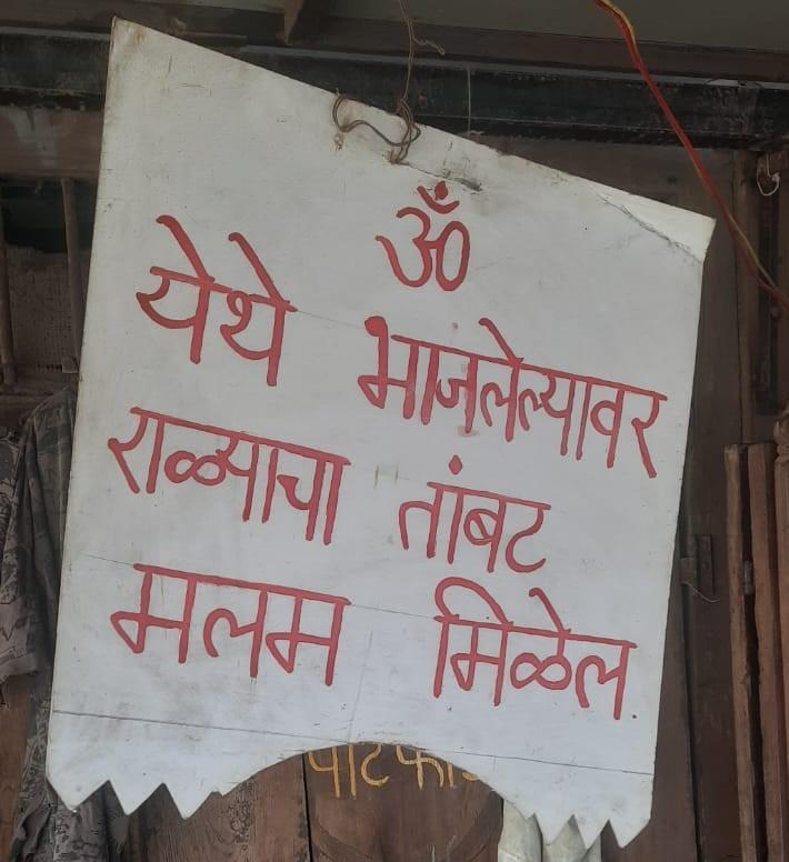 Community board listing artisan services, placed alongside a vegetable stall  in Tambat Ali. (Source: CKA Archives)