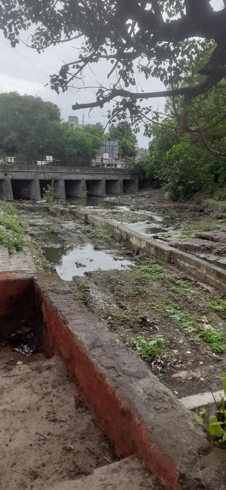 The Mandir overlooks the Ramnadi, which runs along the back side of the property. The riverbed is partially dry, with visible debris and seasonal overgrowth.(Source: CKA Archives)