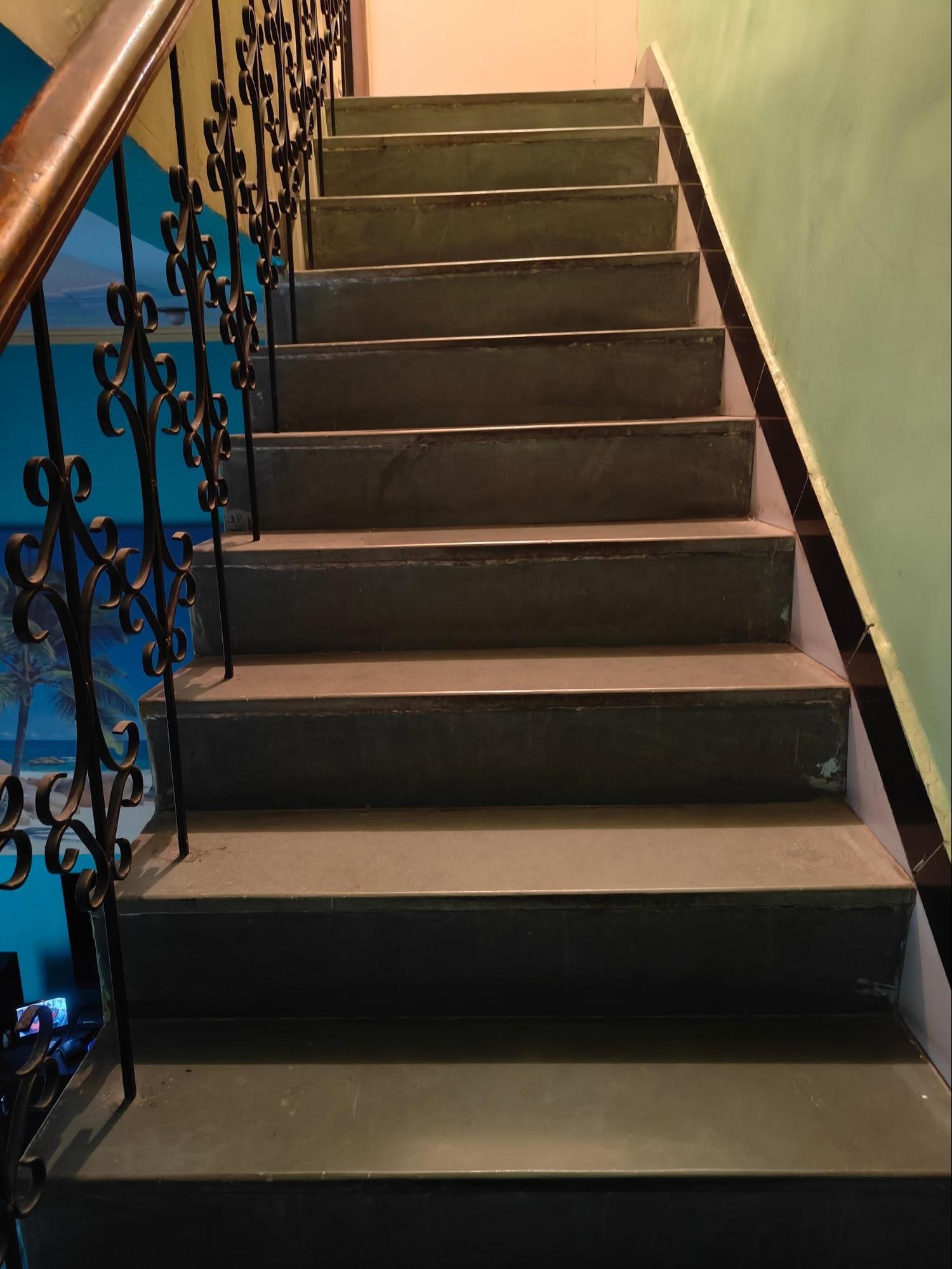 Interior staircase with decorative wrought iron balusters connecting the home's multiple levels, combining structural necessity with ornamental metalwork. (Source: CKA Archives)