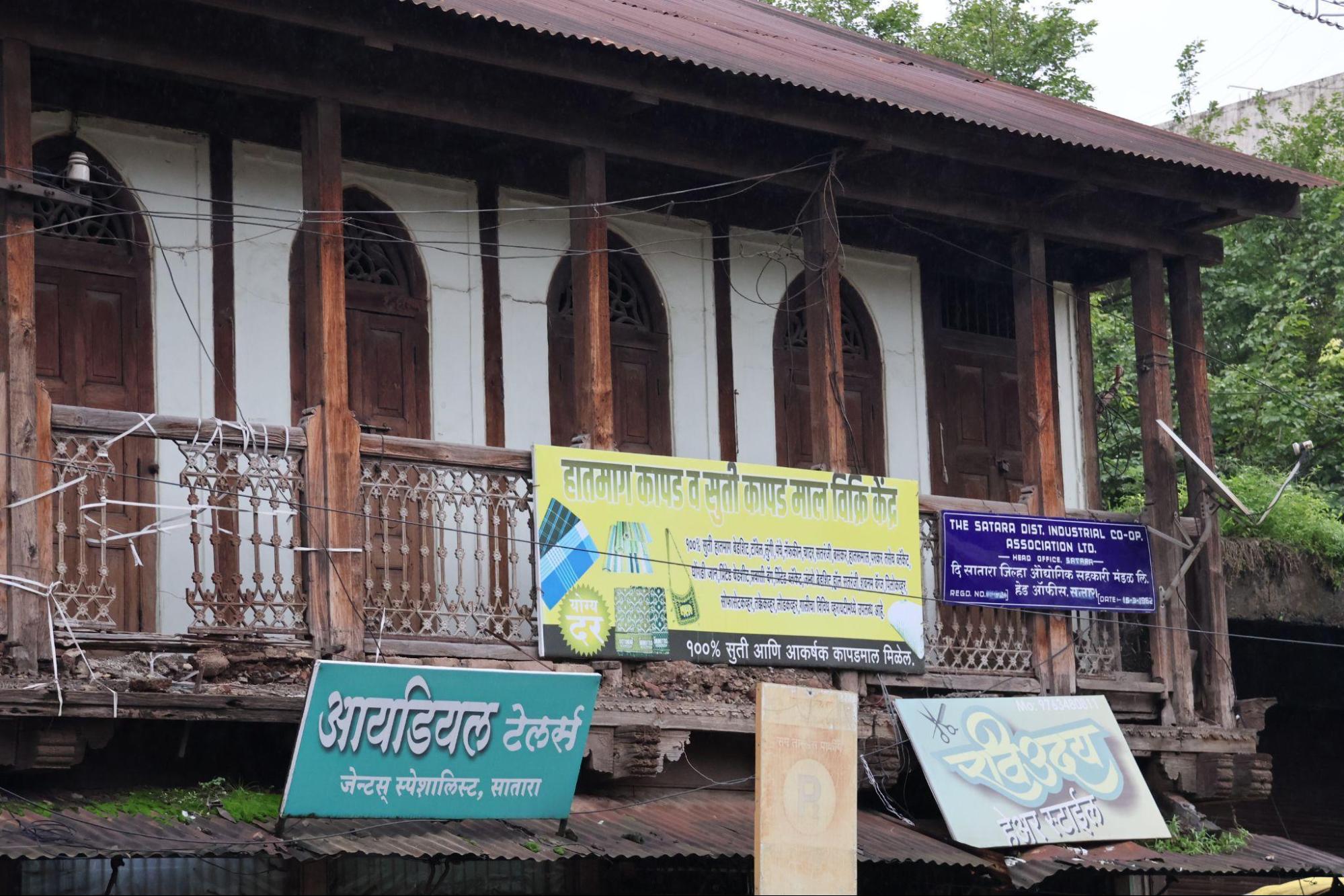 Balcony with decorative cast iron railings and timber supports. Modern advertisement boards occupy part of the upper railing. Notice the uniformity in the design language here, indicating that this area is a shared space.(Source: CKA Archives)
