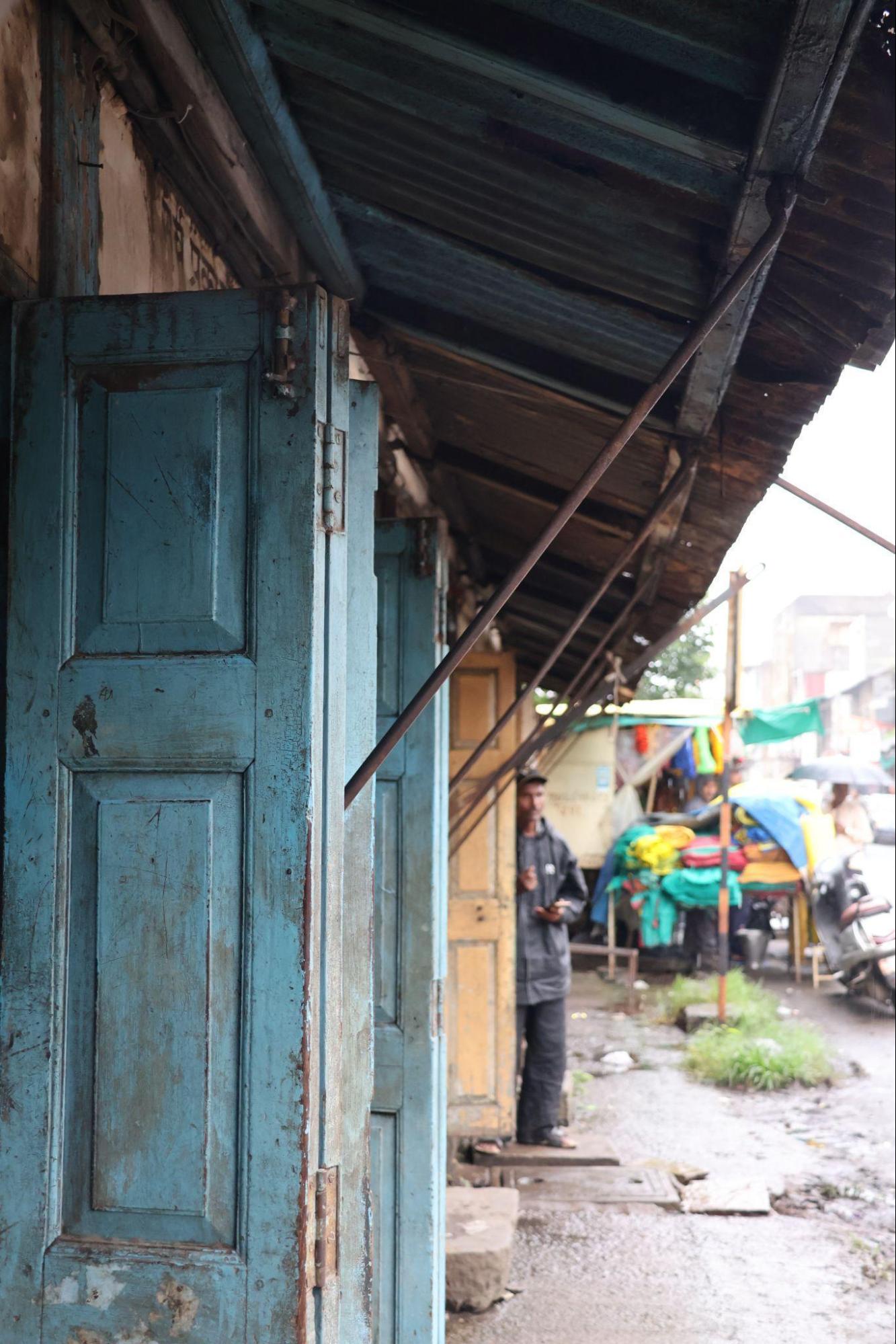Ground-floor shop front with wooden panel doors. Above, the metal-sheet roof is supported by a distinct framework.(Source: CKA Archives)