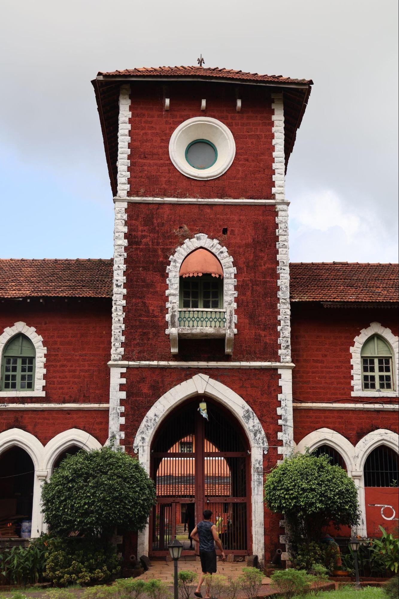 The central tower features a pointed archway, a round oculus window, and a small balcony inspired by traditional jharokhas. These elements, combined with the symmetrical layout and use of red laterite stone, reflect a blend of local building practices and colonial-era design influences. (Source: CKA Archives)