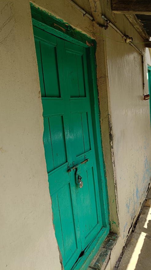 Bright green wooden door on the inside of the house secured with a latch bolt. (Source: CKA Archives)