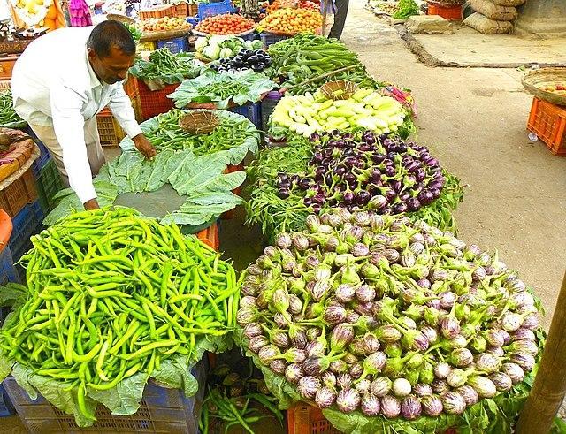 A man arranging produce on display at an open-air farmer's market