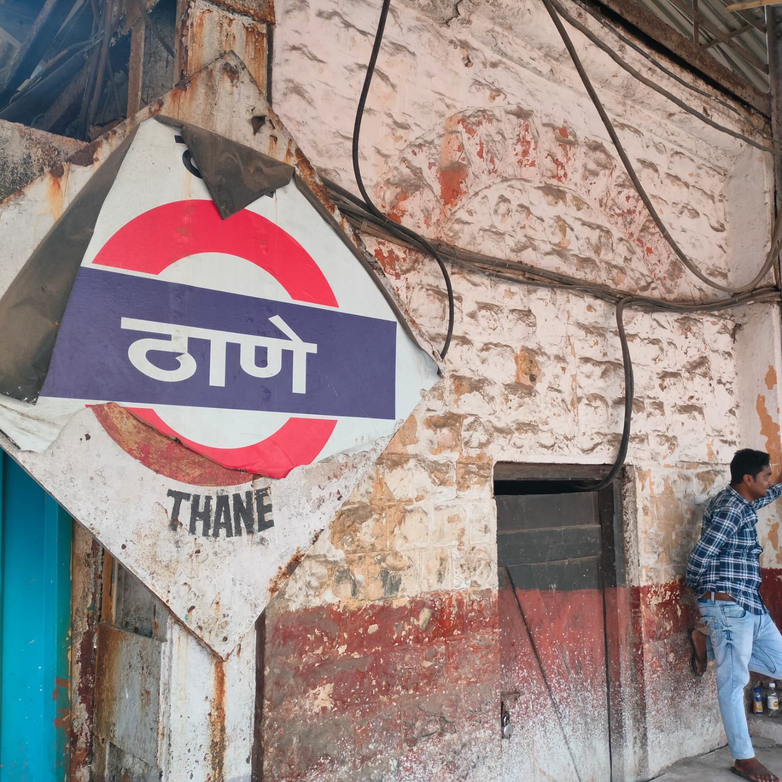 Thane Station signboard with colonial-era stone architecture in the background.